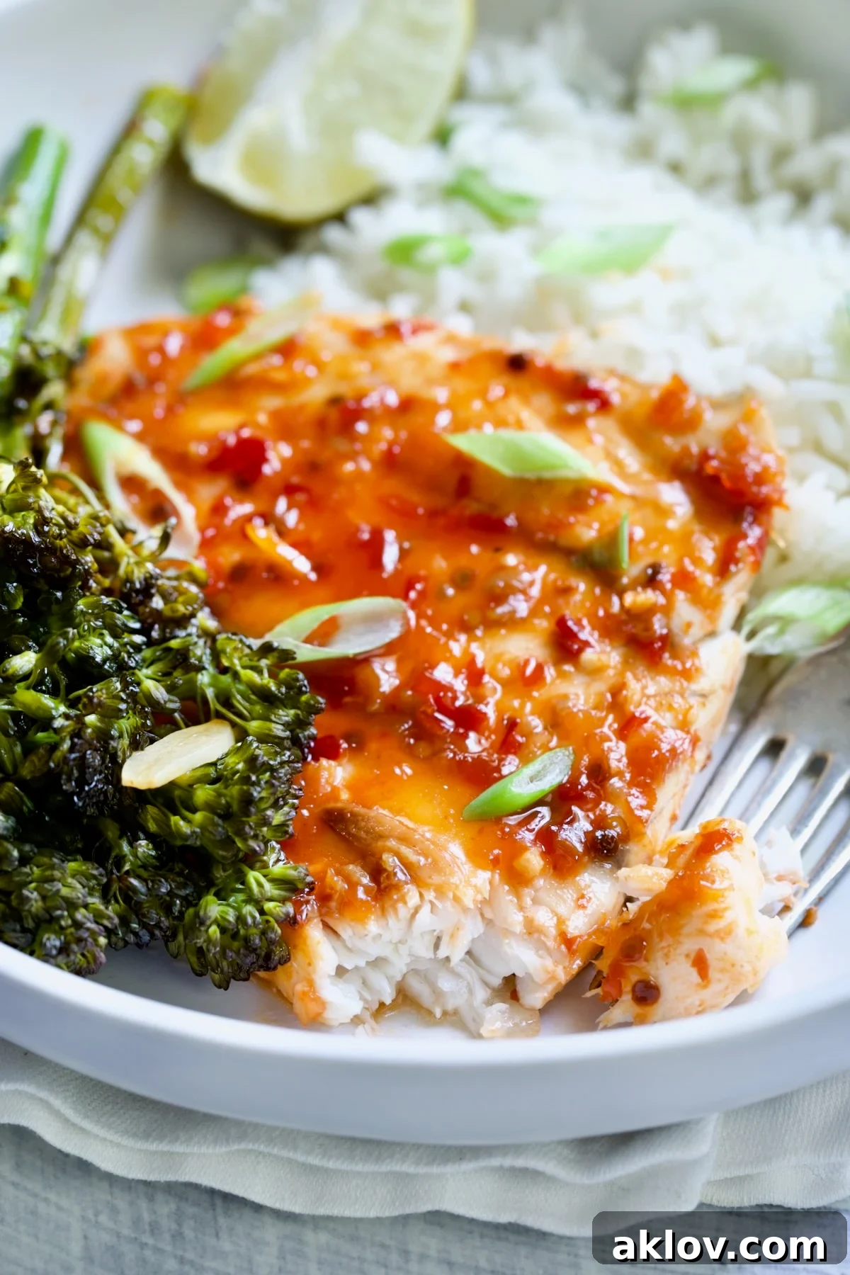 Sheet Pan Thai Baked Fish with Broccolini on white plate with fork garnished with scallions.