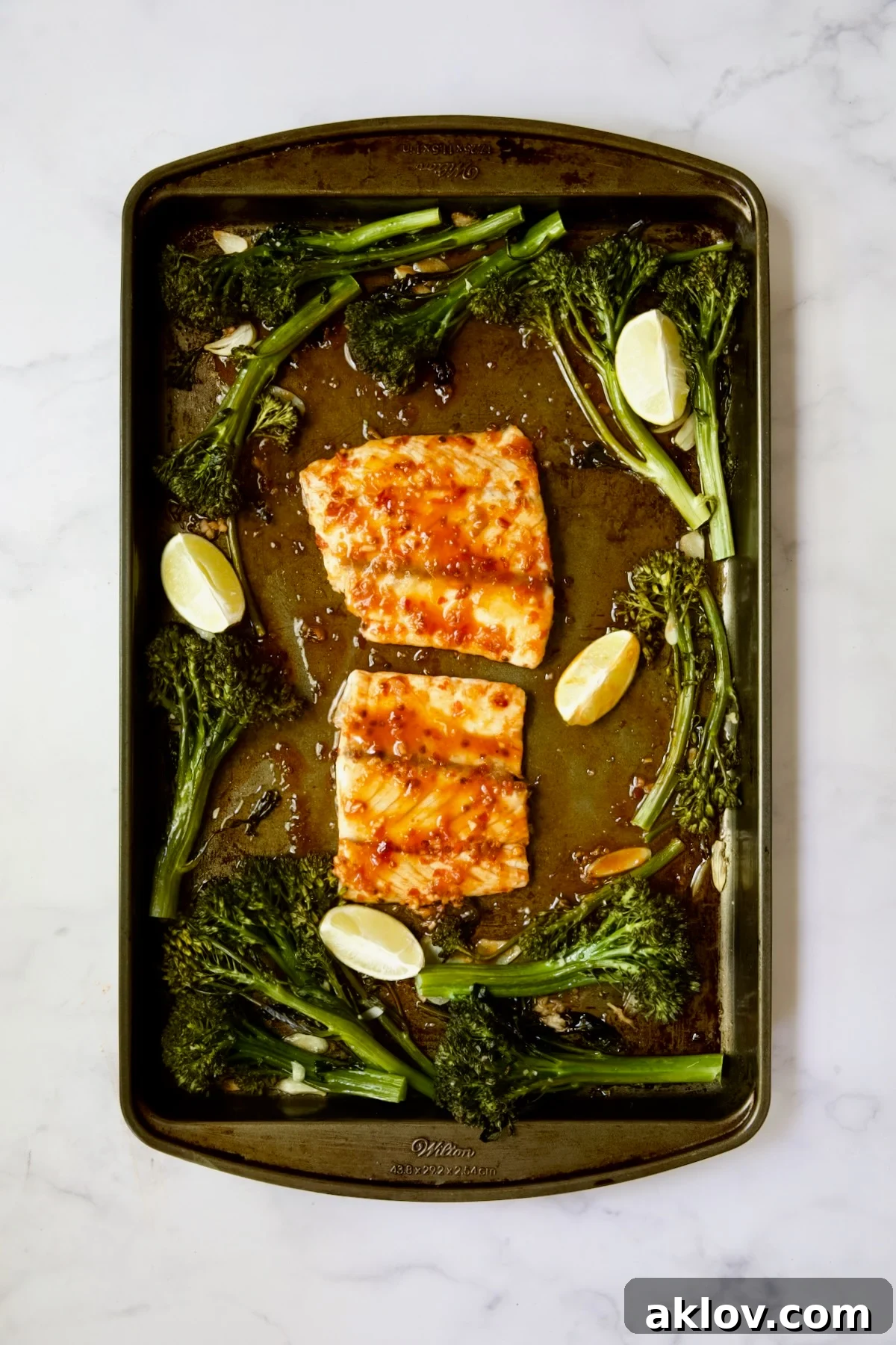 Broccolini and two pieces of fish on rimmed sheet pan after being baked.