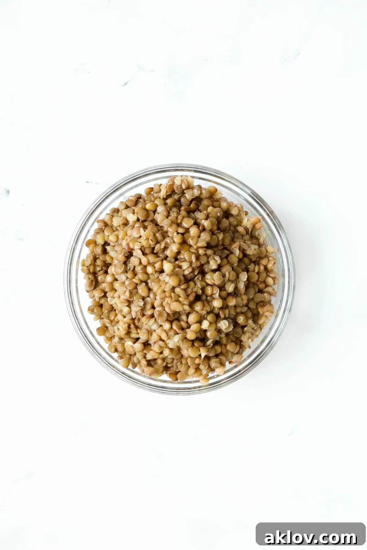Cooked brown lentils presented in glass bowls, showing their tender texture.