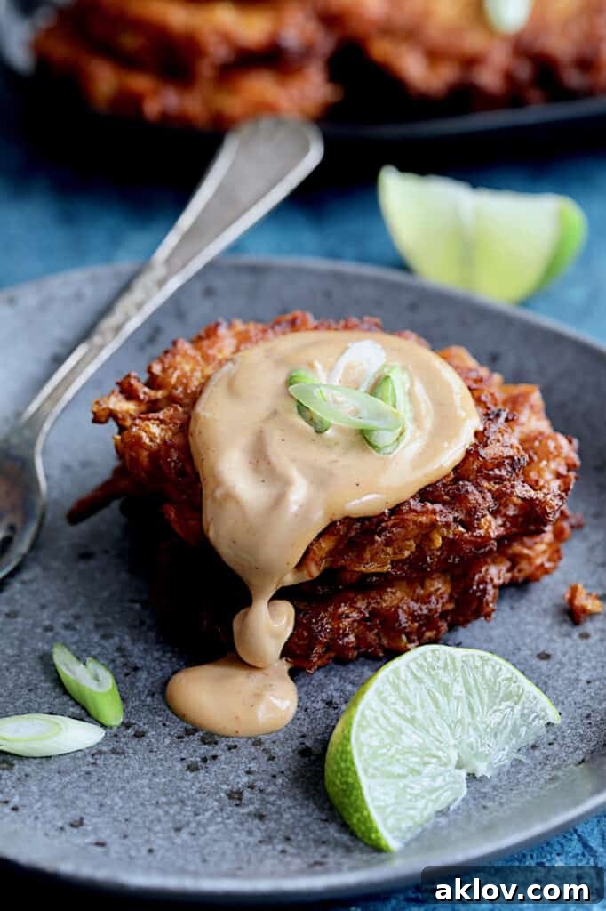 Crispy Sweet Potato Latkes with Fiery Gochujang Aioli 11 Close-up photo of two Korean Sweet Potato Latkes with Gochujang Mayonnaise on gray plate with mayonnaise dripping down.