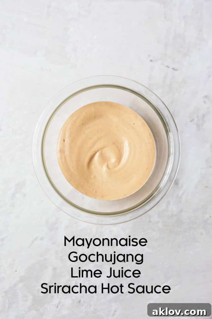 Gochujang Mayonnaise in a glass bowl with ingredients displayed nearby, highlighting its creamy texture.