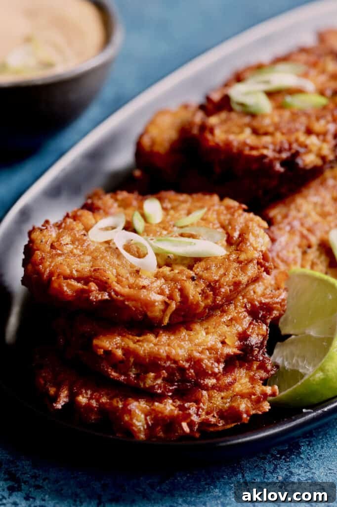A stack of three Korean Sweet Potato Latkes with Gochujang Mayonnaise, accompanied by a fresh lime wedge.