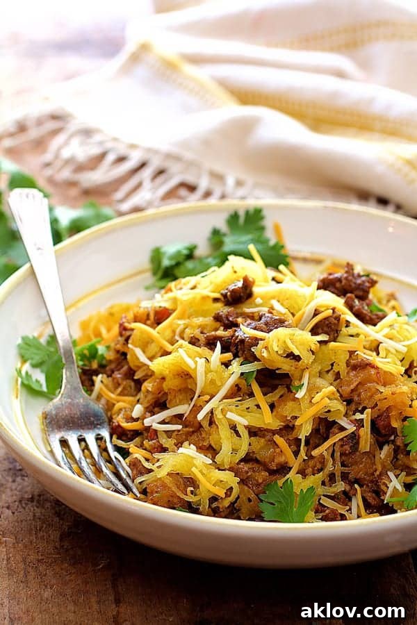 A generous serving of Spaghetti Squash Fideos, garnished with fresh cilantro, presented in a white bowl with a yellow striped towel draped in the background, showcasing the dish's vibrant flavors.