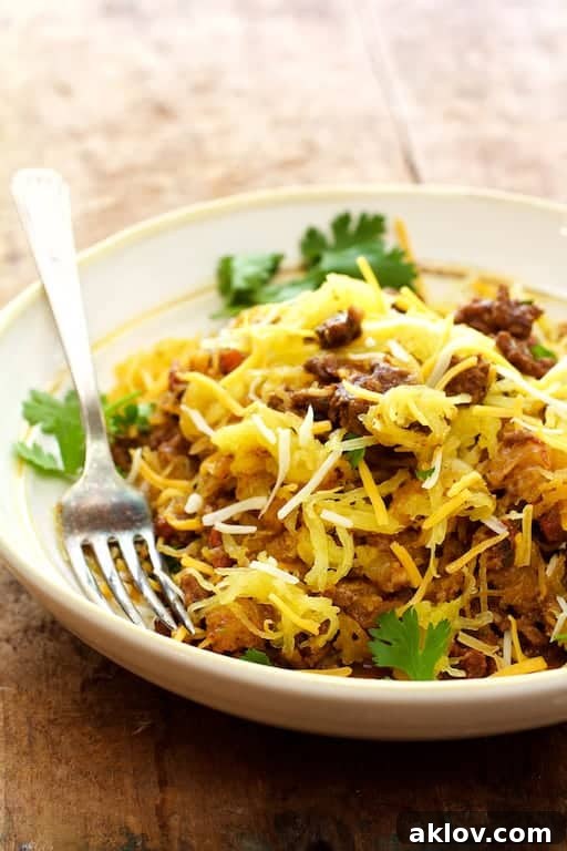 A close-up shot of Spaghetti Squash Fideos in a white bowl, garnished with vibrant cilantro sprigs, highlighting the appetizing texture and rich color of the dish.