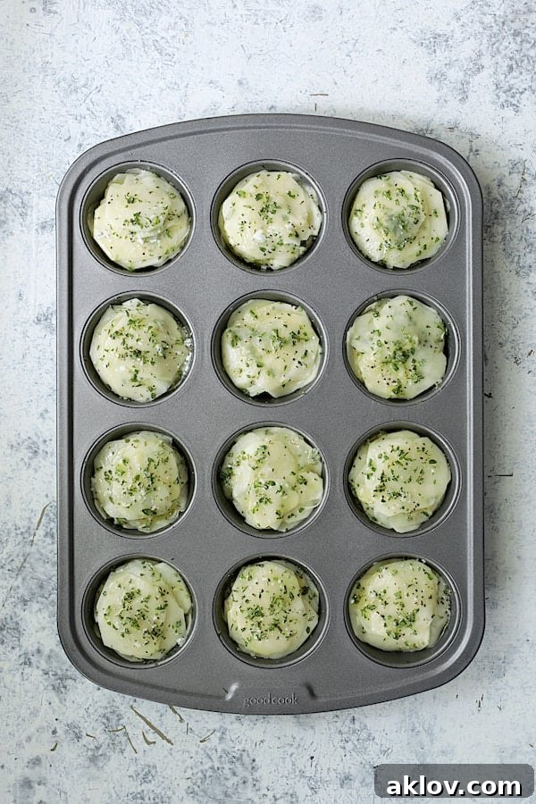 Golden Garlic Herb Potato Galettes in a Muffin Tin 7 A 12-cup muffin pan filled with meticulously stacked, thinly sliced potato rounds, each cup forming a mini galette.