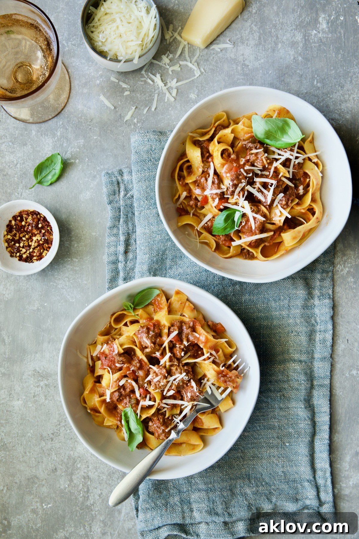 Two bowls of Slow Cooker Spicy Sausage and Pepper Ragu on blue napkin.