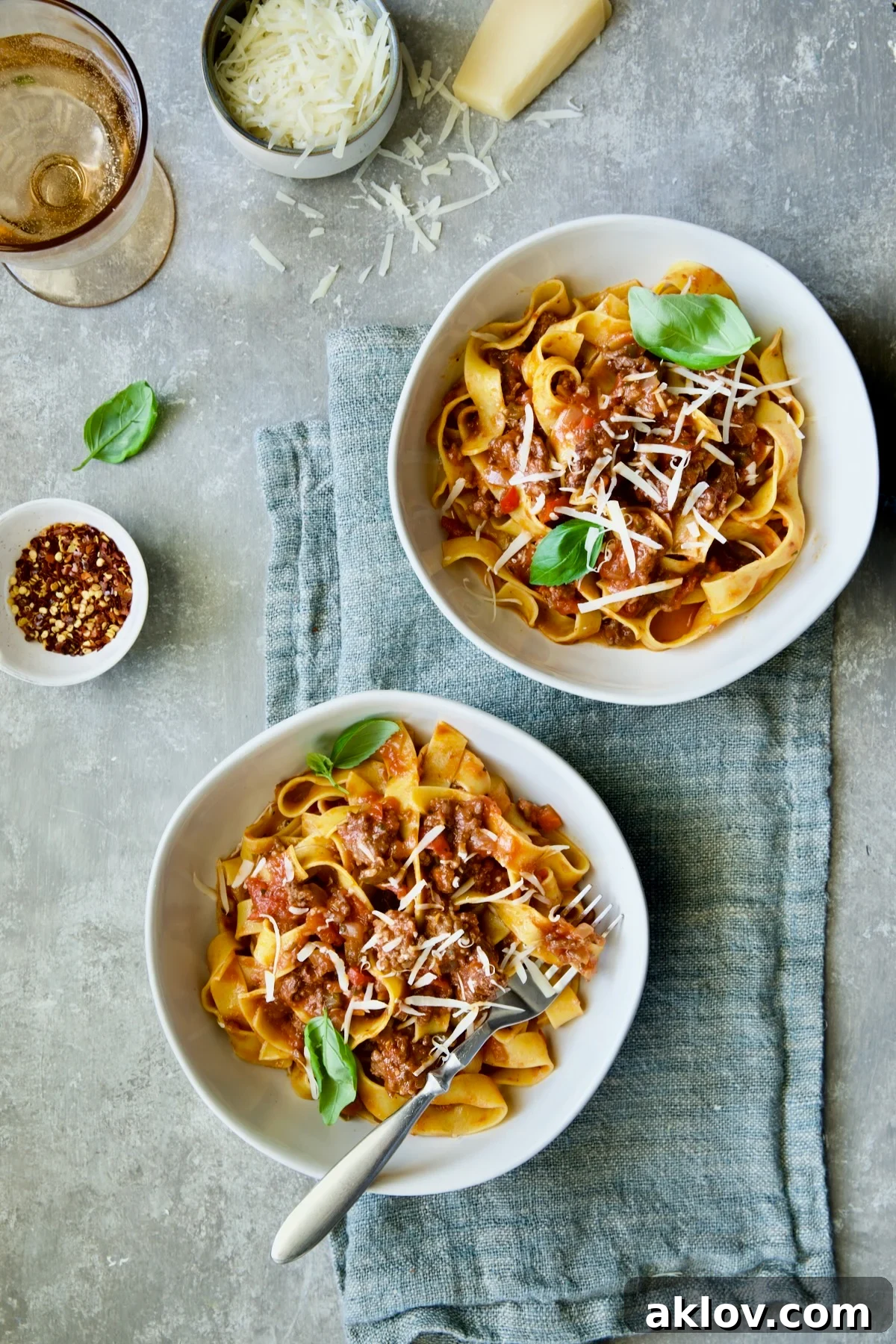 Two bowls of Slow Cooker Spicy Sausage and Pepper Ragu on blue napkin.