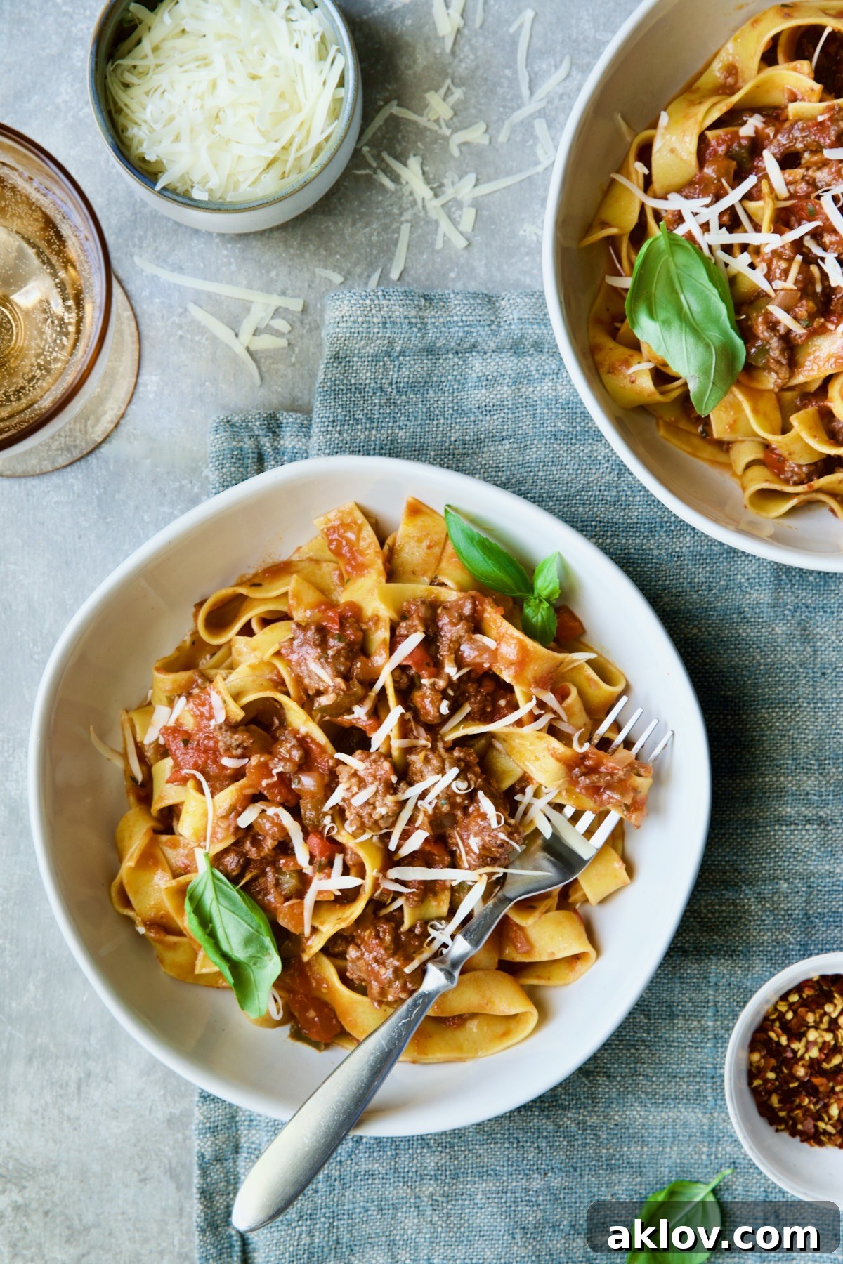 Slow Cooker Spicy Italian Sausage Ragu in bowls sprinkled with cheese and garnished with fresh basil.