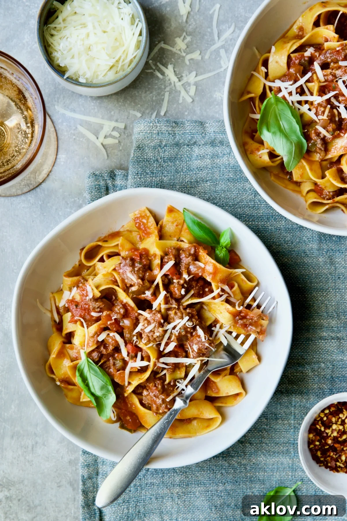 Slow Cooker Spicy Italian Sausage Ragu in bowls sprinkled with cheese and garnished with fresh basil.