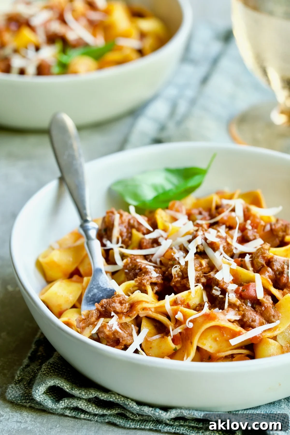 Slow Cooker Spicy Sausage and Pepper Ragu over pappardelle in white bowl with fork.