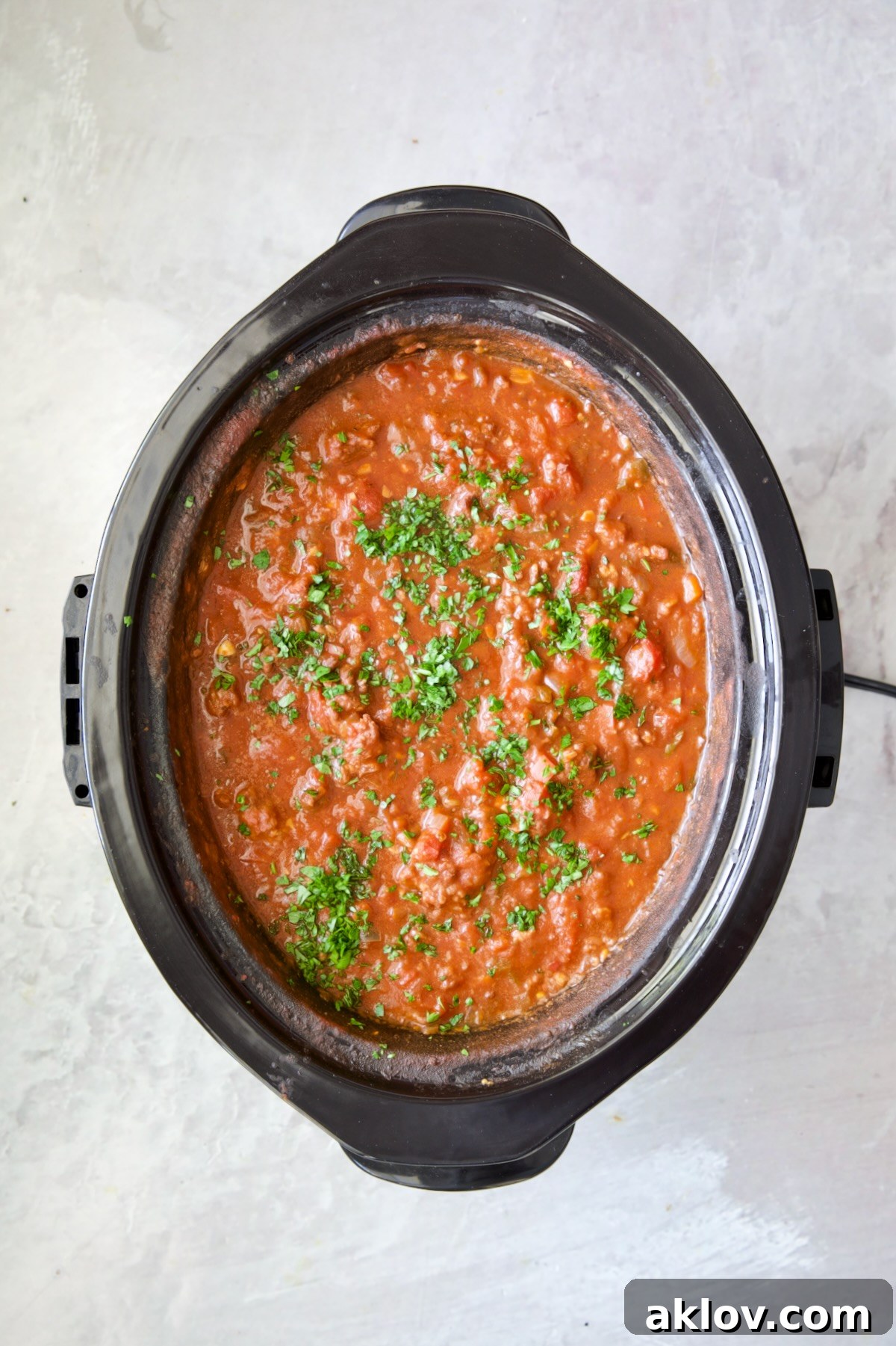 Slow Cooker Spicy Sausage and Pepper Ragu in slow cooker garnished with fresh parsley.