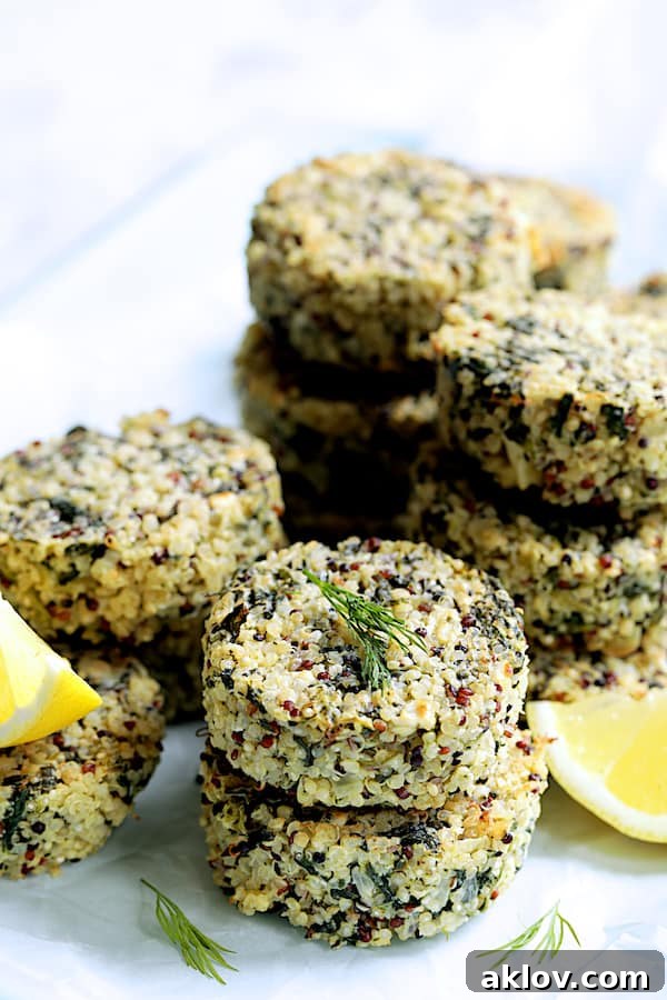 Close-up photo of Greek Quinoa Cakes stacked with lemon wedges and dill sprigs.