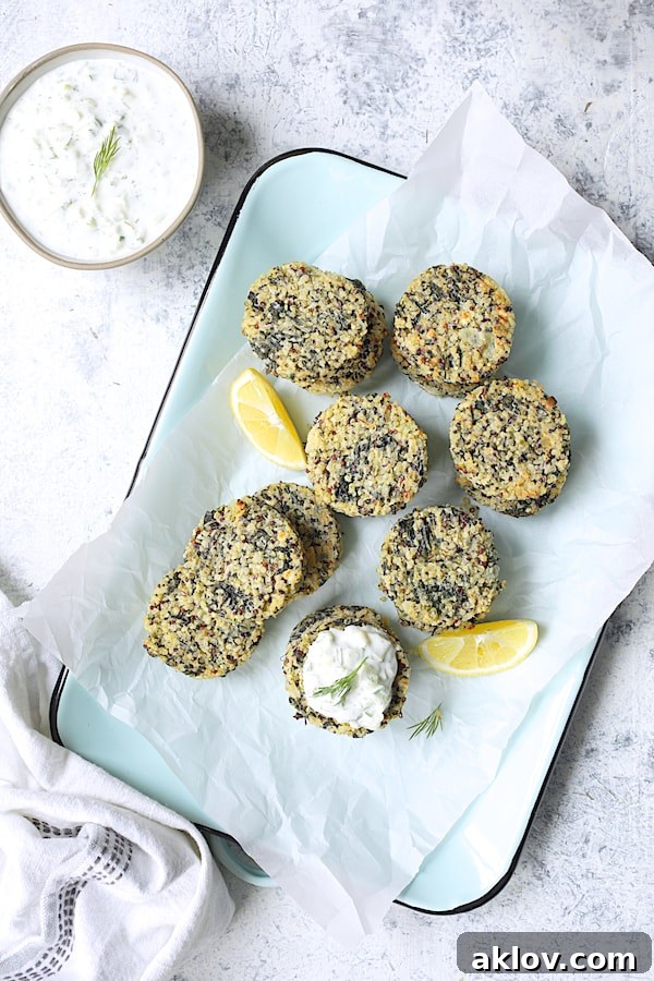 Photo of Greek Quinoa Cakes with Tzatziki on parchment paper-lined light blue platter with lemon wedges.