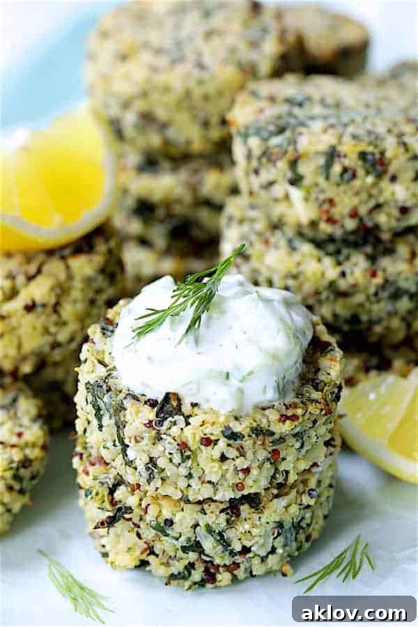 Close-up photo of two stacked Greek Quinoa Cakes with Tzatziki garnished with lemon wedges and dill sprigs.