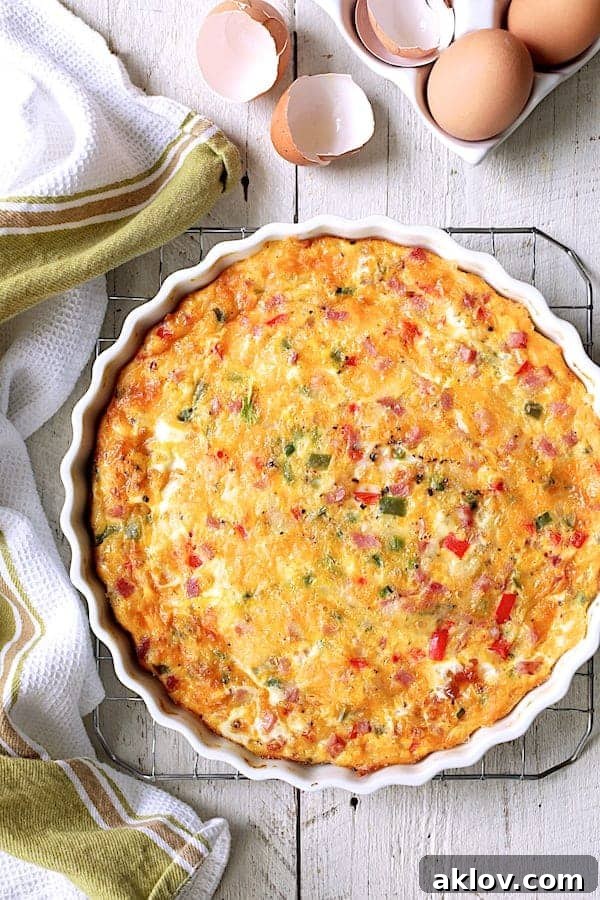 Photo of whole Spicy Baked Denver Omelet on cooling rack with eggs and eggshells nearby.