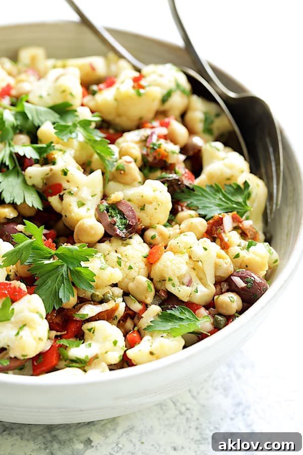 Photo of Sicilian Cauliflower Salad in white serving bowl garnished with parsley sprigs.