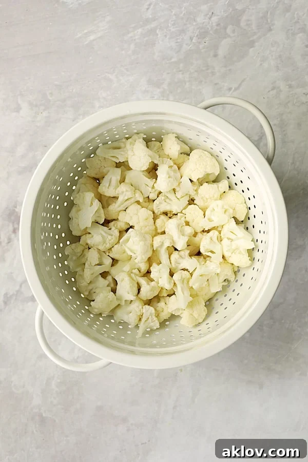 Photo uncooked cauliflower florets in white colander.
