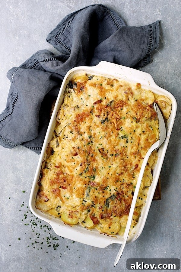Hearty Country-Style Potato Cabbage Casserole with Cheddar and Bacon in a white baking dish, presented with a blue towel and a white serving spoon.