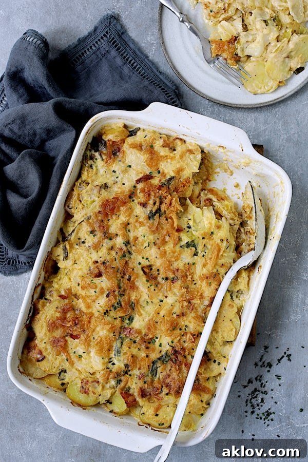 A serving of Potato Cabbage Casserole with Cheddar and Bacon plated on a round white dish, ready to be enjoyed.