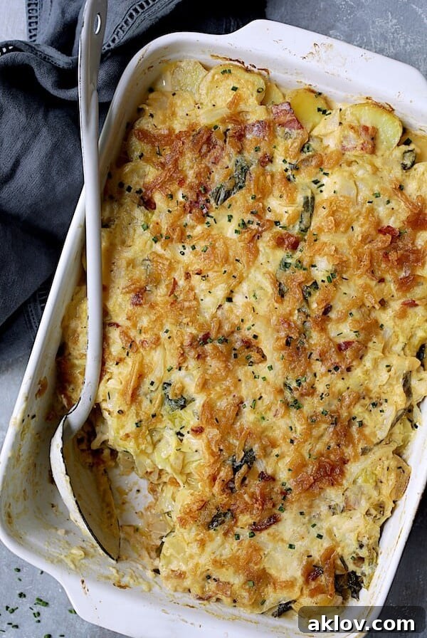 Country-Style Potato and Cabbage Casserole with Cheddar and Bacon in white rectangular baking dish with white serving spoon.