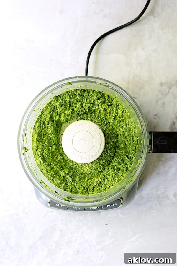 Photo of smooth spinach pesto in food processor bowl after blending.