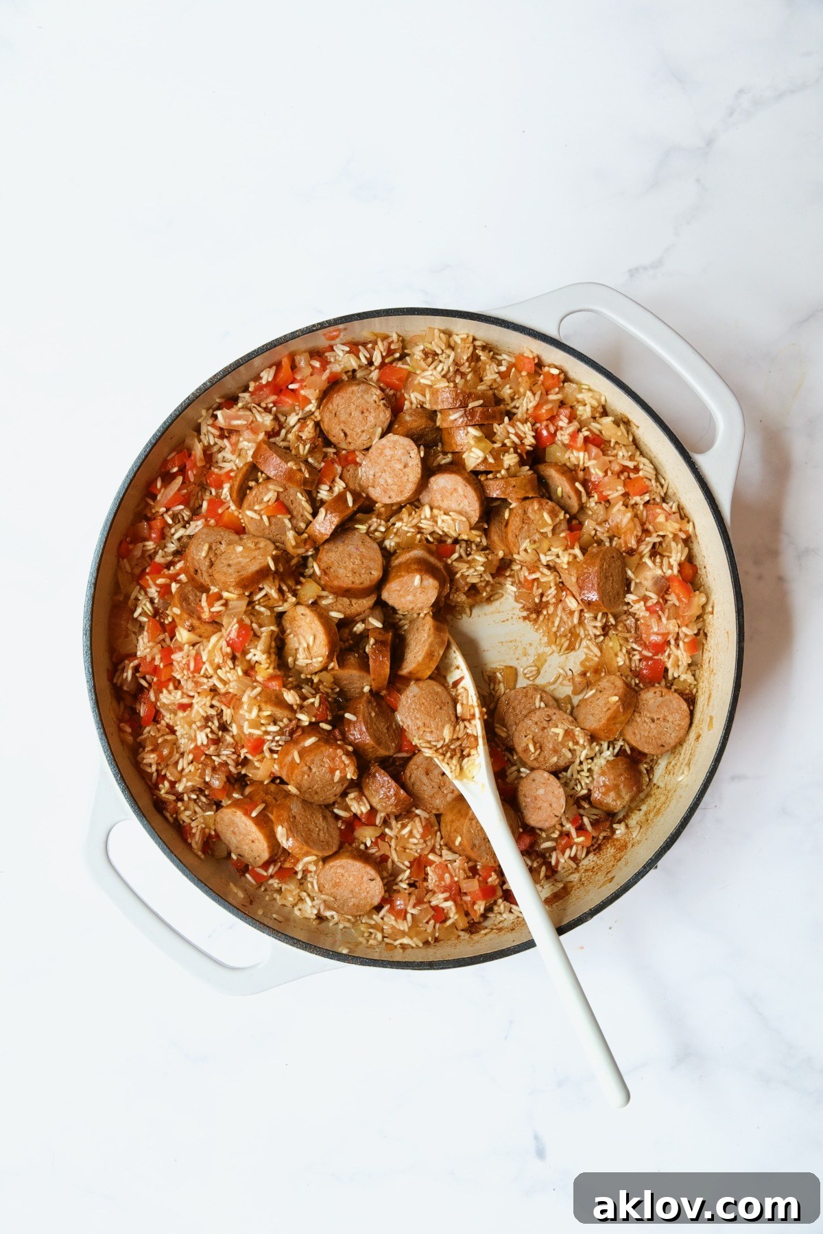 Process shot with chorizo sausage slices added back into the paella pan.