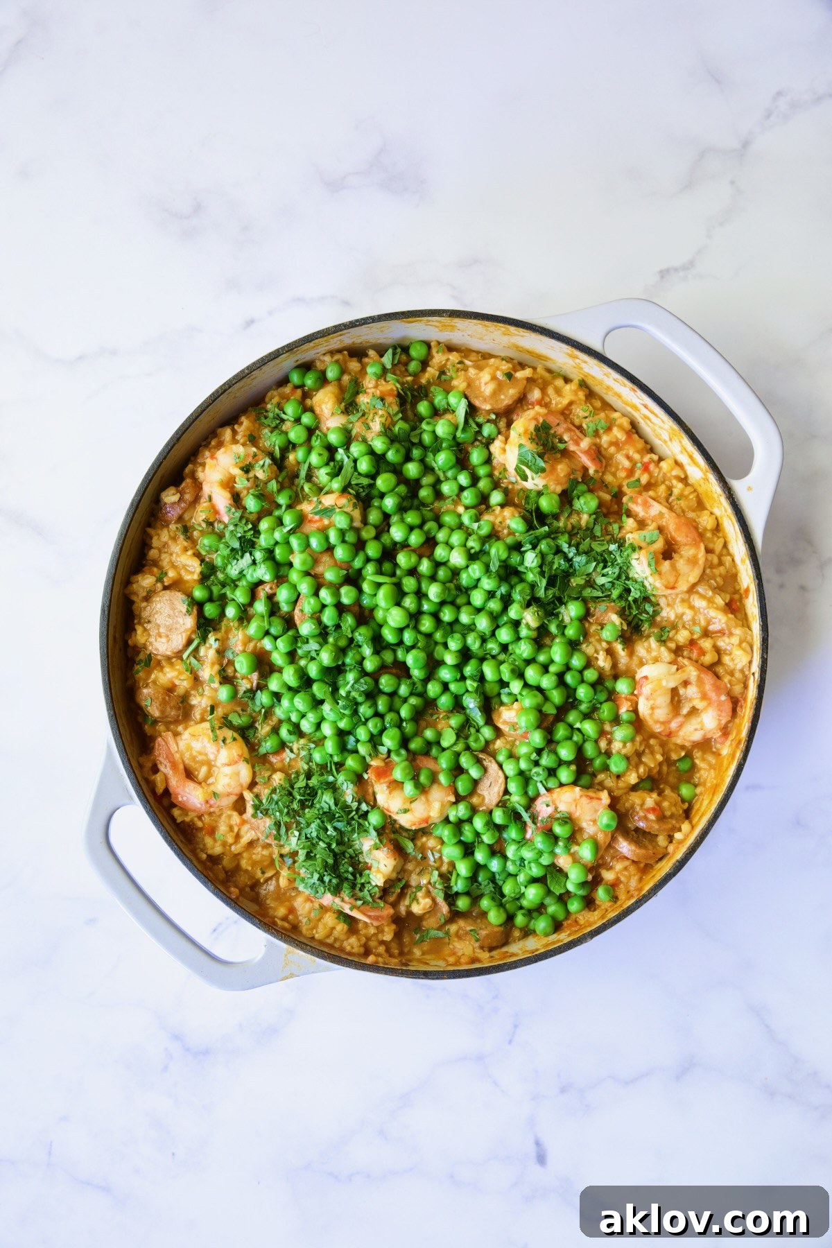 Process shot of paella with peas added.
