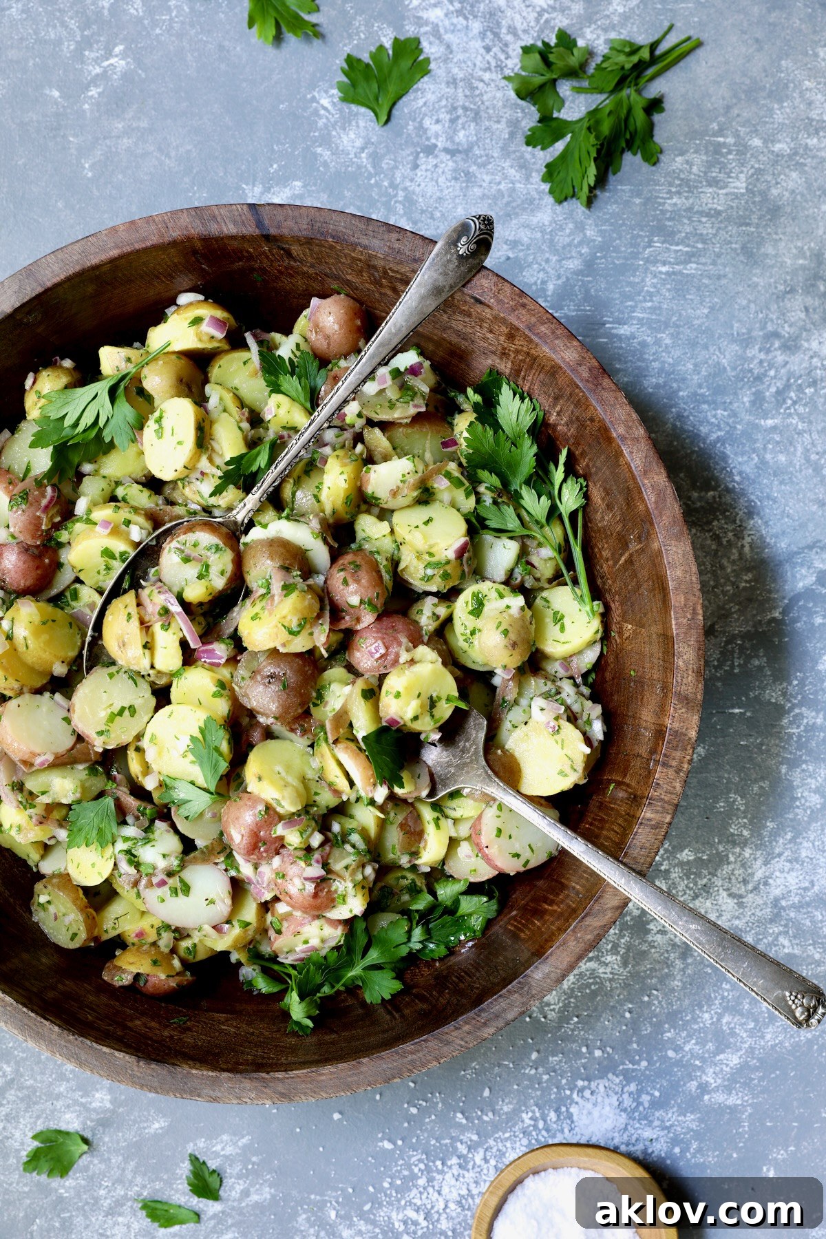 French Potato Salad presented in a beautiful wooden bowl, garnished with fresh parsley and a sprinkle of sea salt, ready to be enjoyed.