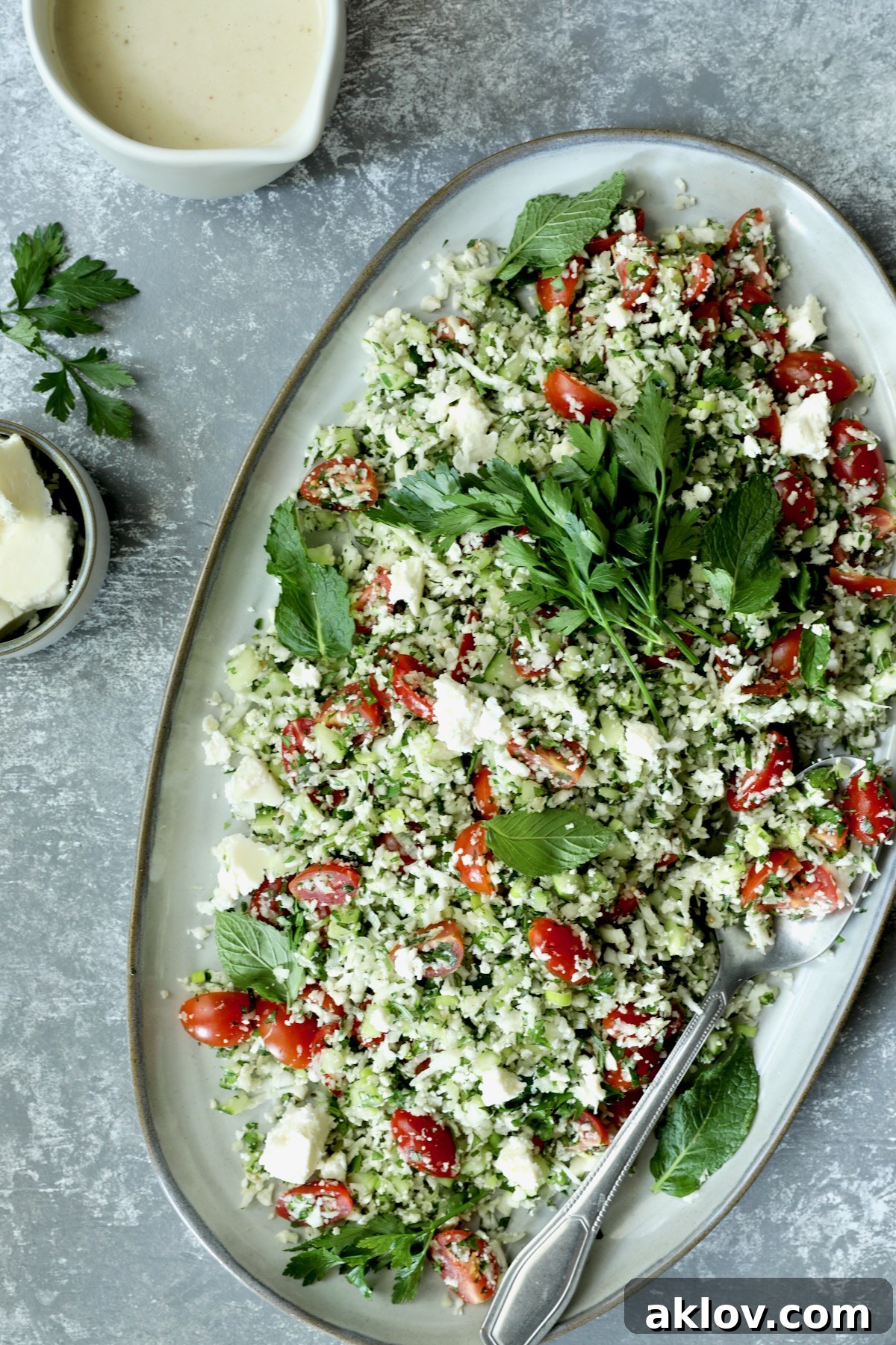 Cauliflower Tabbouleh on a decorative platter with a serving spoon, showcasing its fresh ingredients.