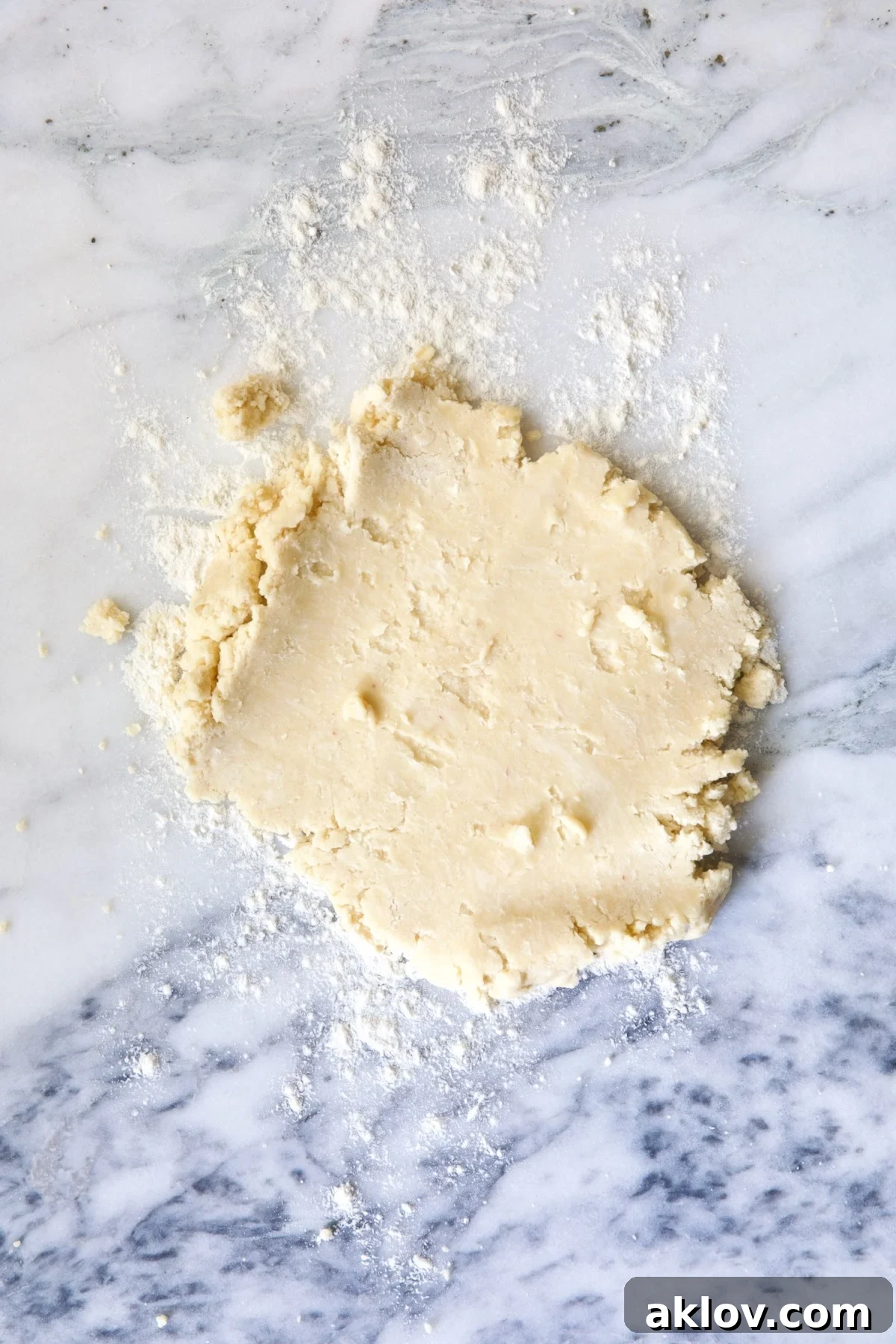 Partially rolled out galette dough on white marble pastry board.