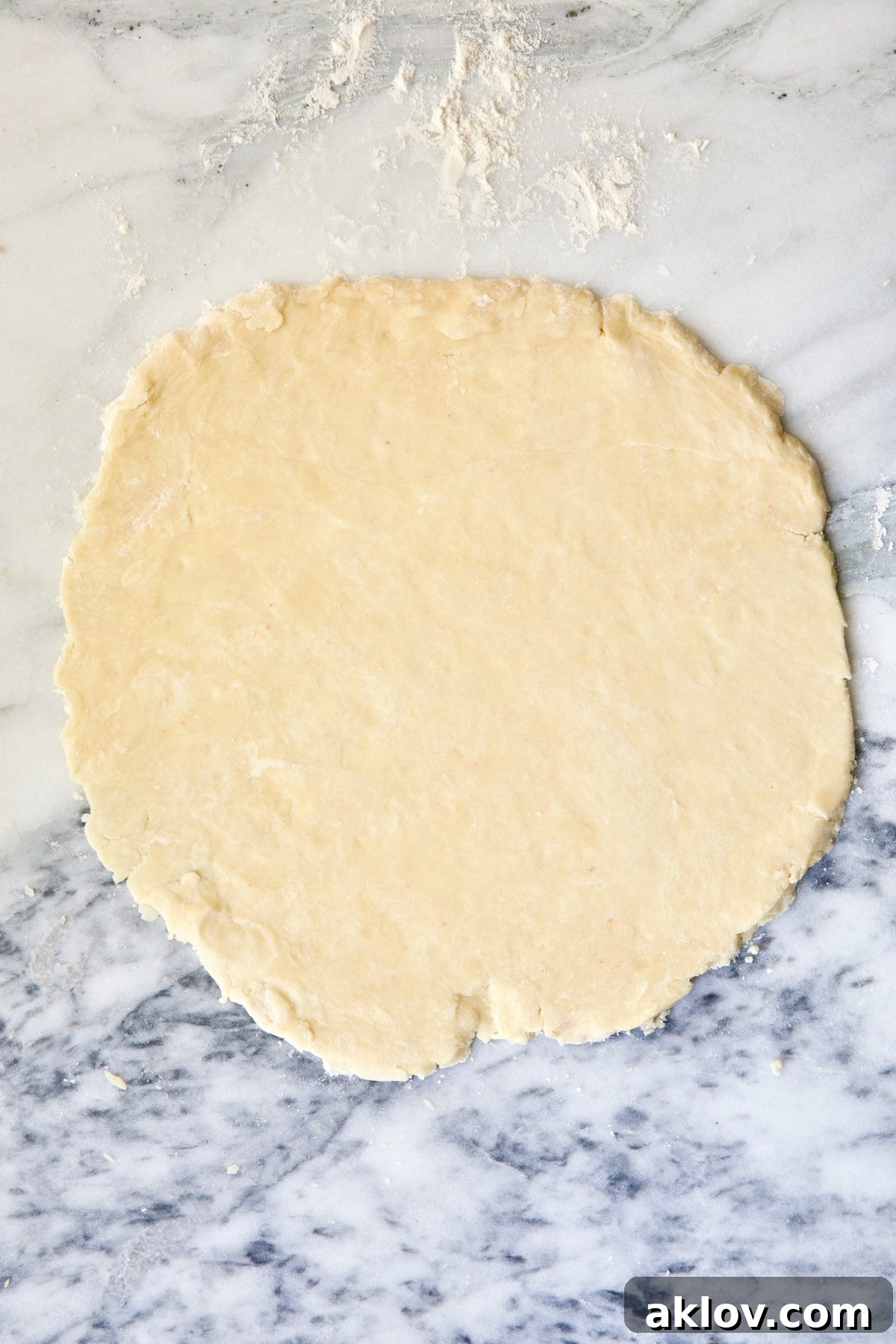 A fully rolled-out circle of galette dough elegantly displayed on a white marble pastry board, ready for filling.