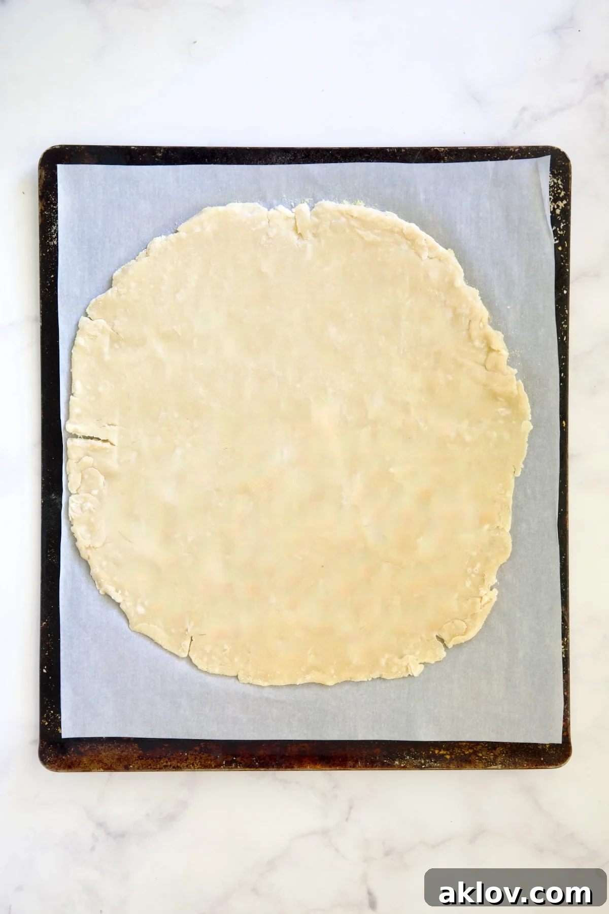 Galette dough before being filled on white parchment paper-lined baking sheet.