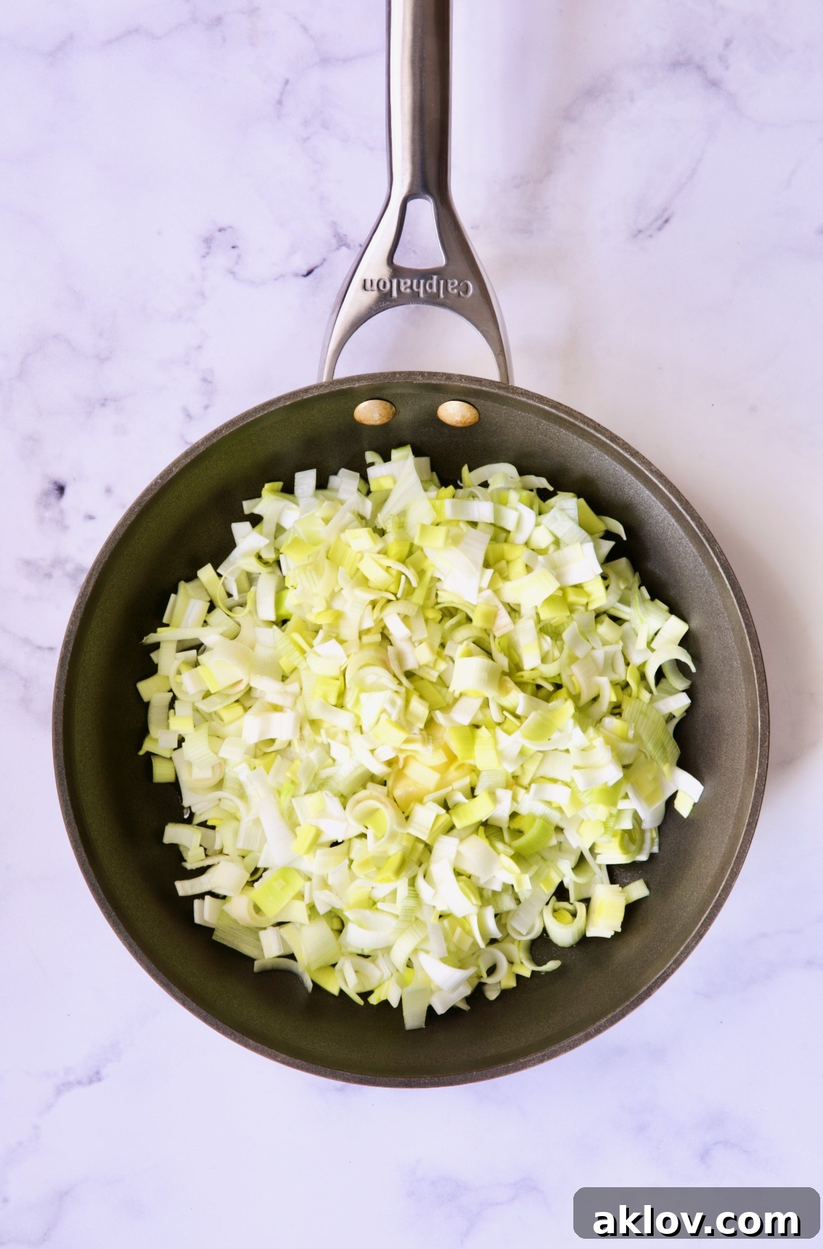 Fresh, uncooked sliced leeks patiently waiting in a nonstick skillet before cooking.