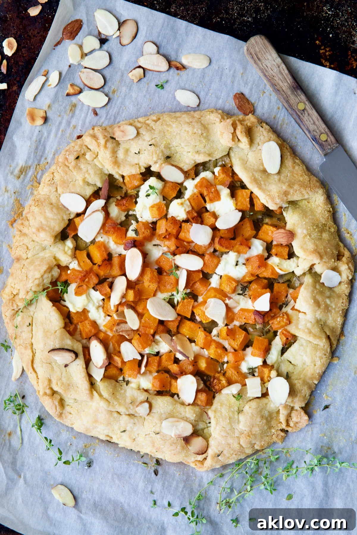 A full, freshly baked Butternut Squash, Leek, and Goat Cheese Galette resting on white parchment paper, ready to be sliced and served.