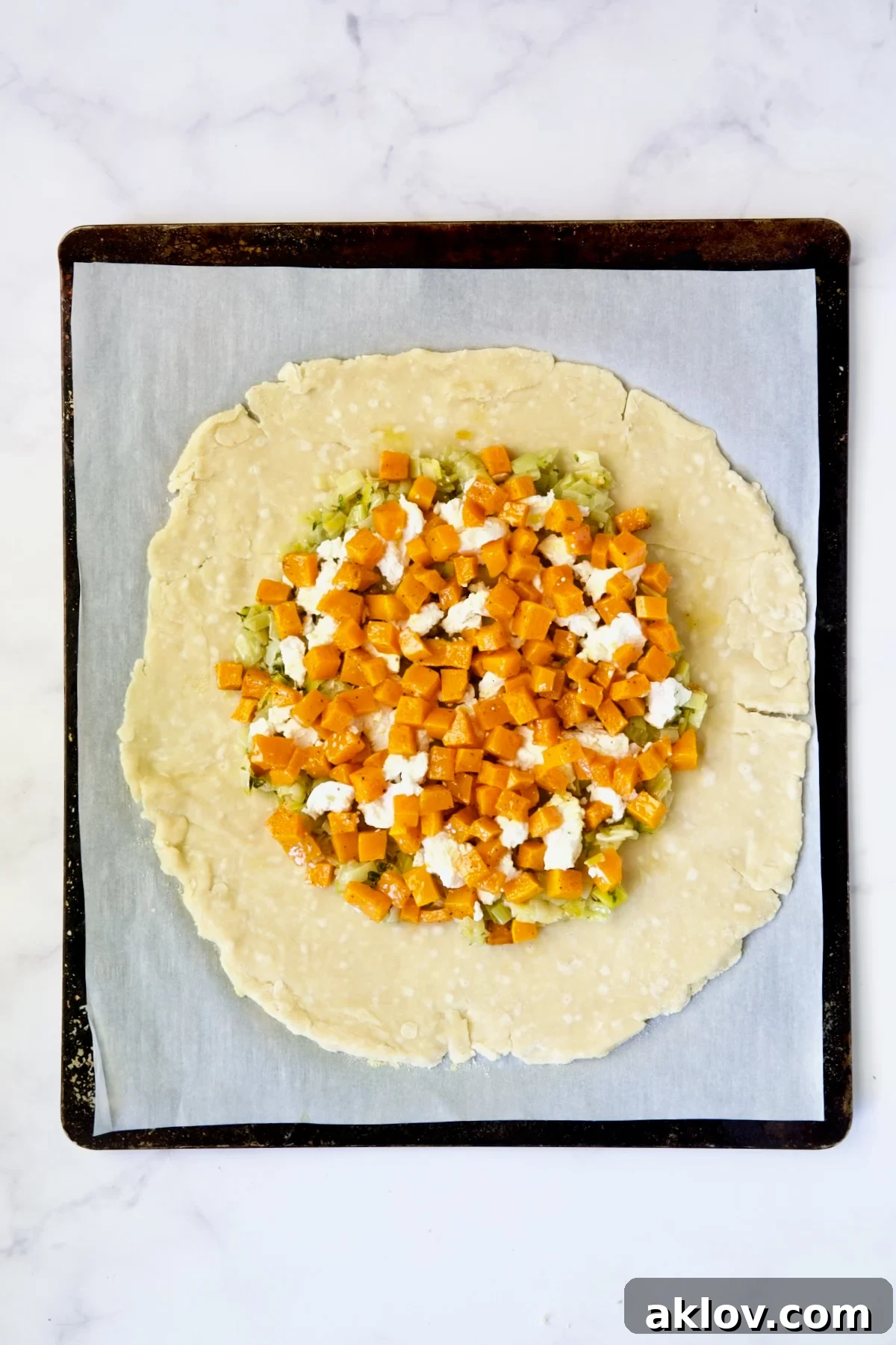 Butternut squash, goat cheese and leeks on galette dough on parchment paper-lined baking sheet.