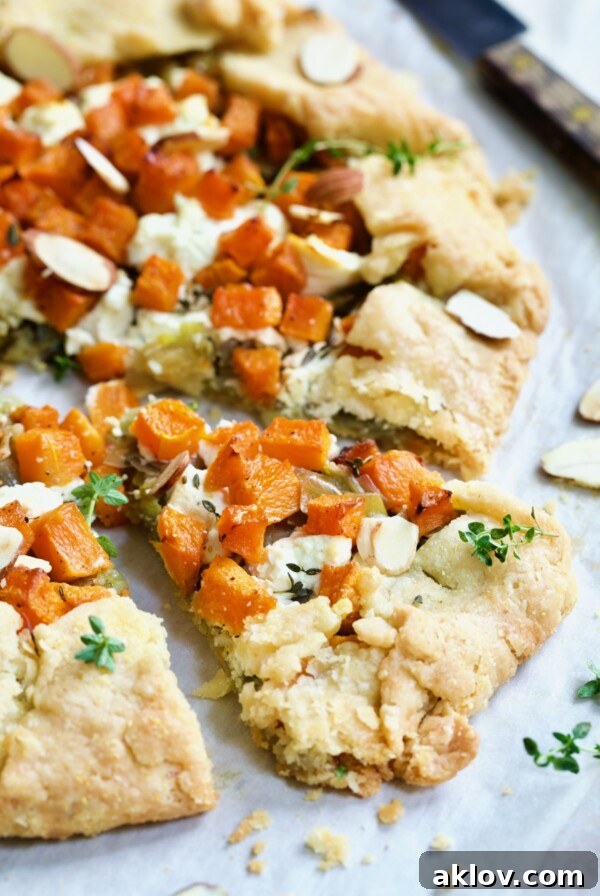 A delicious wedge of Butternut Squash, Leek, and Goat Cheese Galette, beautifully garnished with fresh thyme, presented from the recipe.