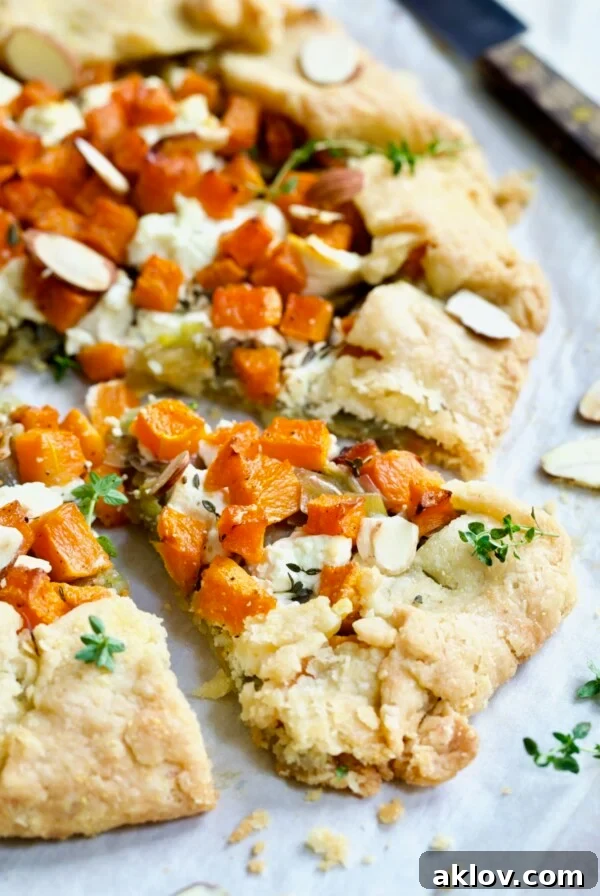 Wedge of Butternut Squash Leek and Goat Cheese Galette garnished with fresh thyme.