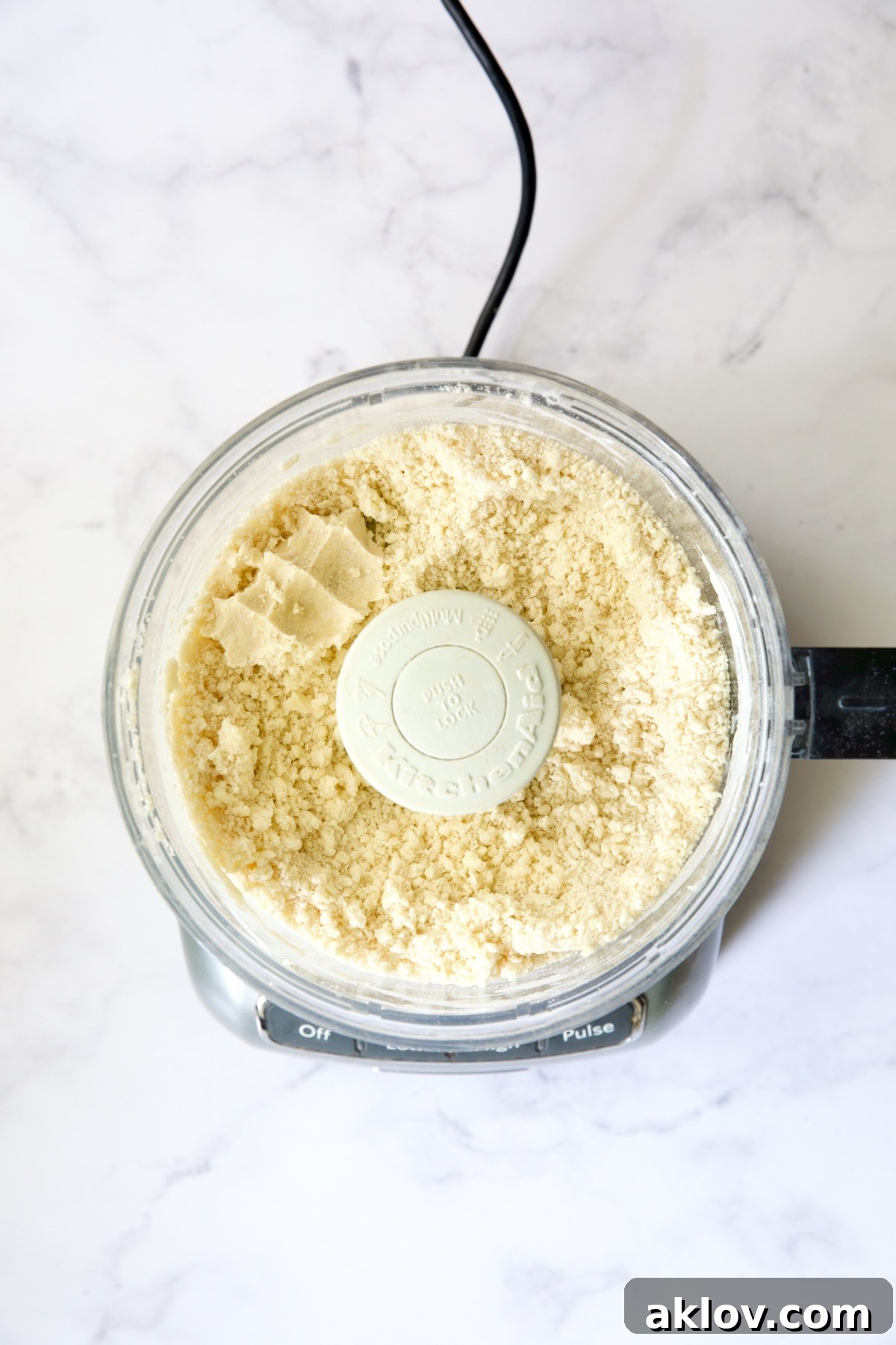 A close-up of galette dough in the food processor, with a small portion pinched together to demonstrate its readiness to hold its shape.