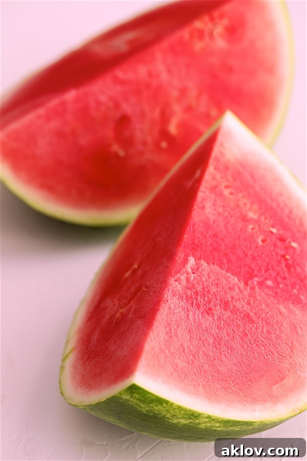 Two vibrant red watermelon wedges, perfectly cut and ready for consumption or culinary use, highlighting the fruit's juicy texture.