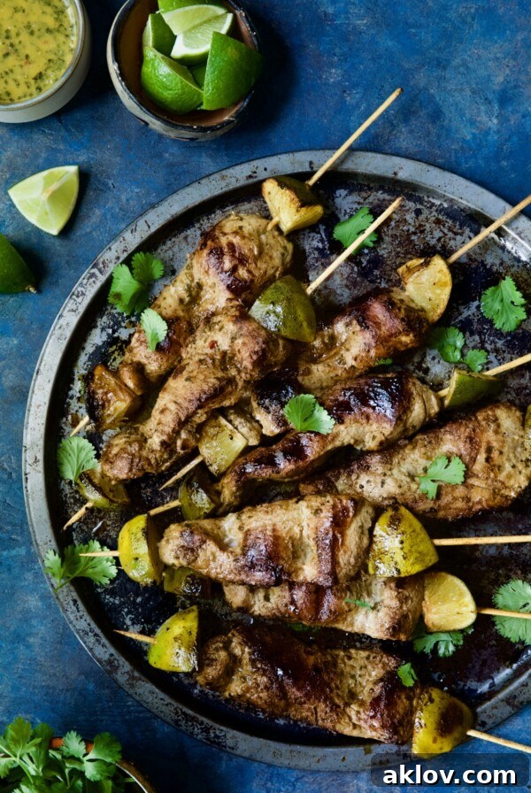 Mojo-Marinated Pork Skewers on metal tray garnished with cilantro.