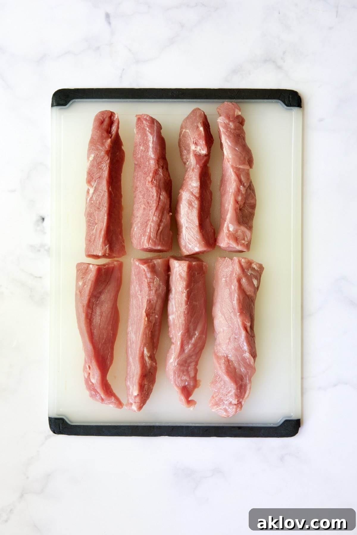 Pork tenderloins expertly cut into eight long, even strips, prepared for marinade.