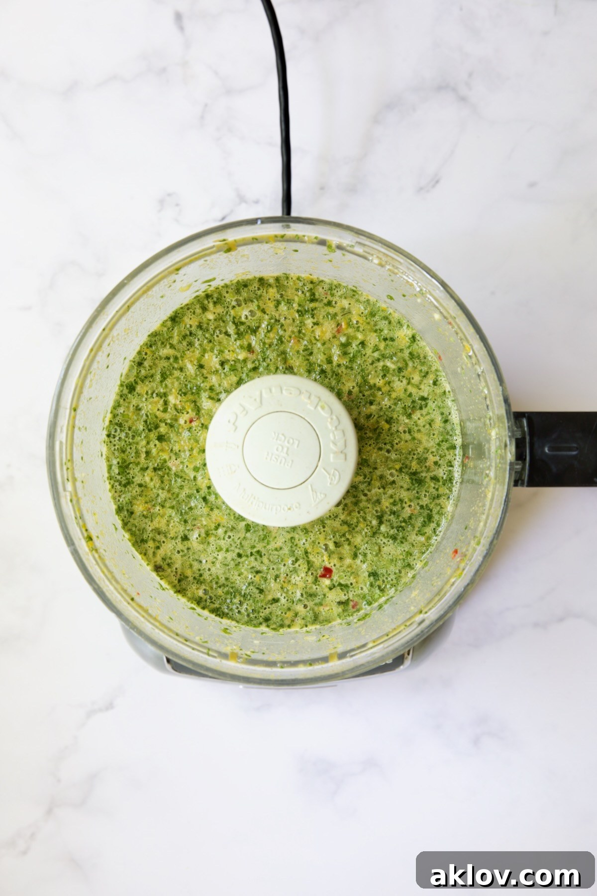 Smooth, vibrant mojo marinade actively blending in a food processor.
