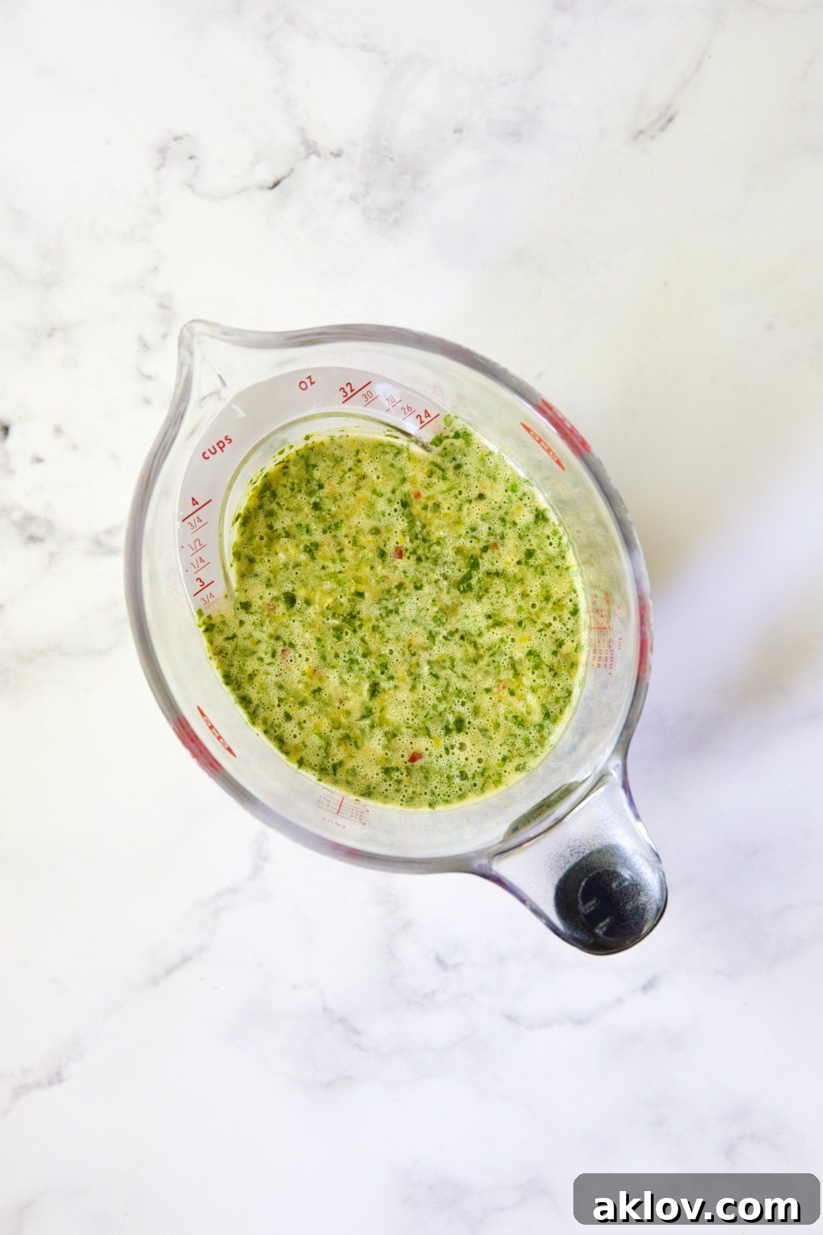 A measuring pitcher filled with the freshly prepared mojo marinade, ready for division.