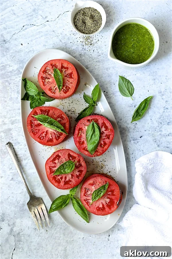 Beautifully arranged tomato stacks on a white oval platter, awaiting dressing and garnishes.