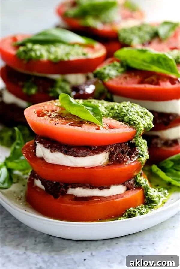 Stacked Tomato Salad with Tapenade and Basil Pesto Dressing - Close-up hero shot on white platter