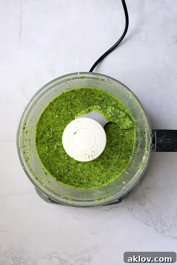 Smooth, vibrant basil pesto dressing being prepared in a food processor.