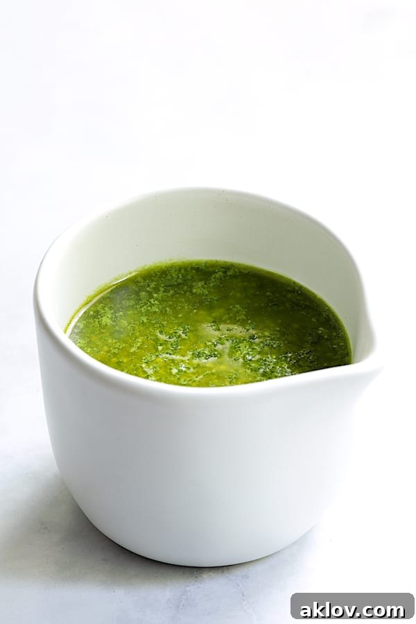 The freshly made basil pesto dressing, poured into a small elegant white pitcher, ready for serving.