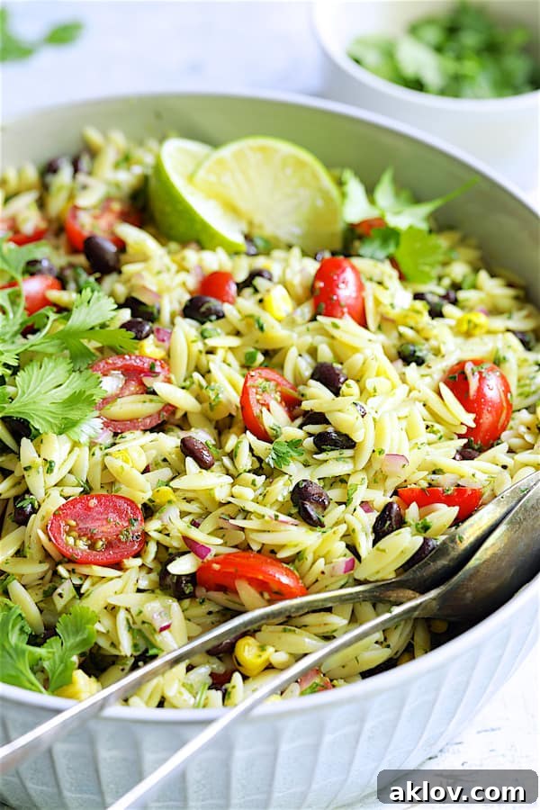 A close-up view of the appetizing Southwestern Orzo Pasta Salad, featuring individual grains of orzo, colorful vegetables, and creamy dressing in a white serving bowl.
