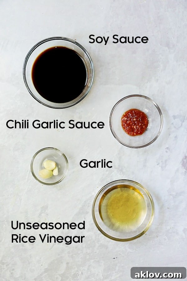 Individual glass bowls holding ingredients for Spicy Garlic Dipping Sauce: soy sauce, rice vinegar, chili garlic sauce, and minced garlic.