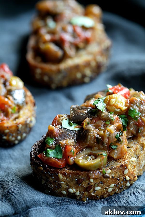 Close-up photo of Moroccan-Spiced Caponata generously piled onto a slice of crusty bread, showcasing its texture.